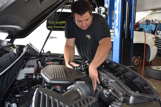 Male mechanic inspecting inside a car hood